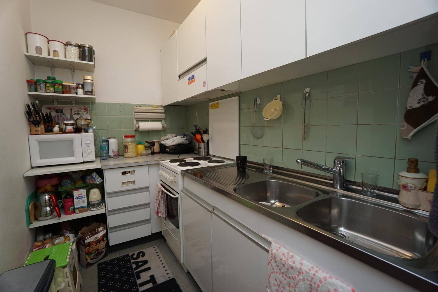 Gemütliches Wohnzimmer mit L-förmigem Sofa, Glastisch und hellem Holzschrank.