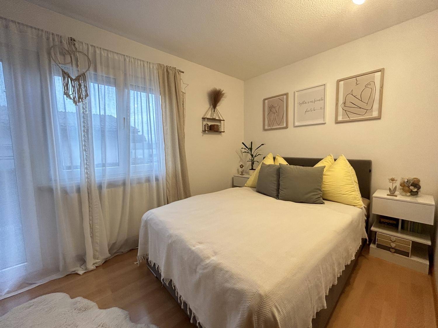 Helles Schlafzimmer mit Doppelbett, Holzboden und minimalistischer Dekoration für eine ruhige Atmosphäre.