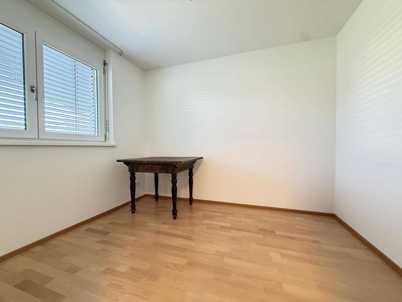 Kleiner, heller Raum mit Holzfußboden und einem Fenster, ideal als Büro oder Gästezimmer.