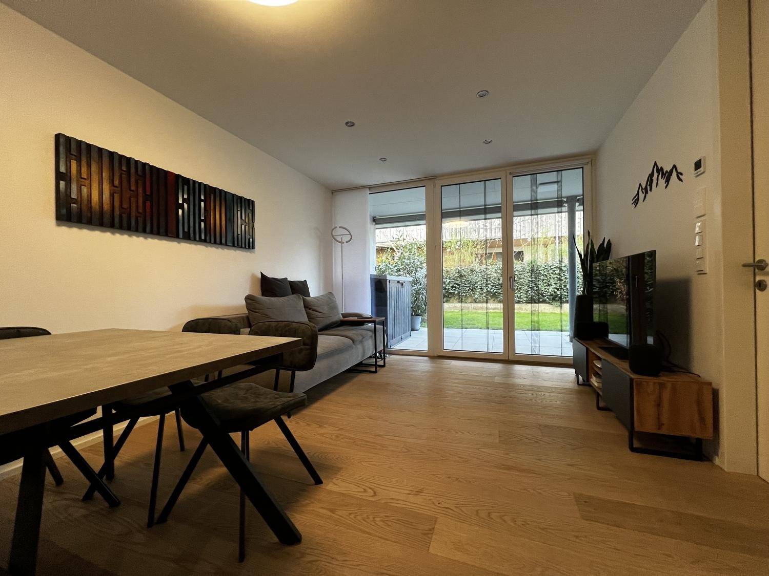 Heller Wohn- und Essbereich mit Holzboden, modernen Möbeln und Zugang zum Garten.