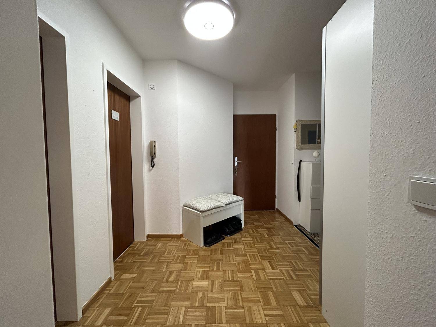 Heller Eingangsbereich mit Parkettboden und praktischer Sitzbank für Schuhe.