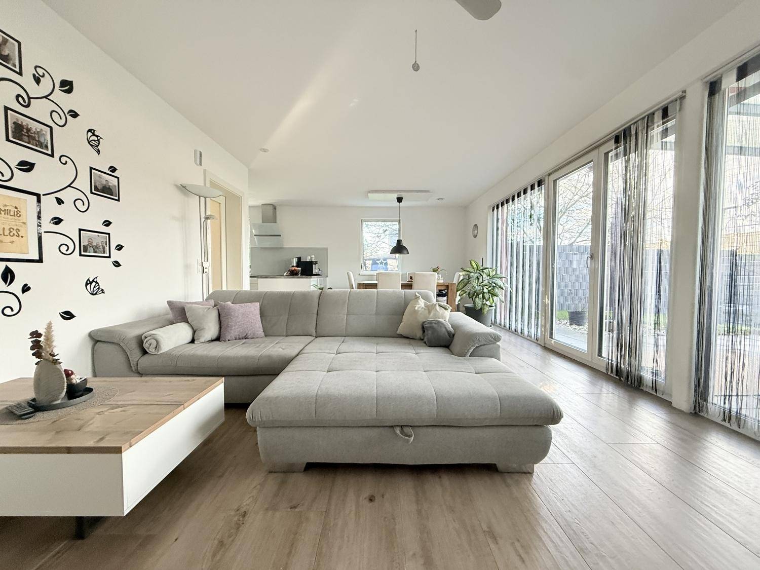 Großzügiger offener Wohn- und Essbereich mit Sofa und Blick zur Küche.