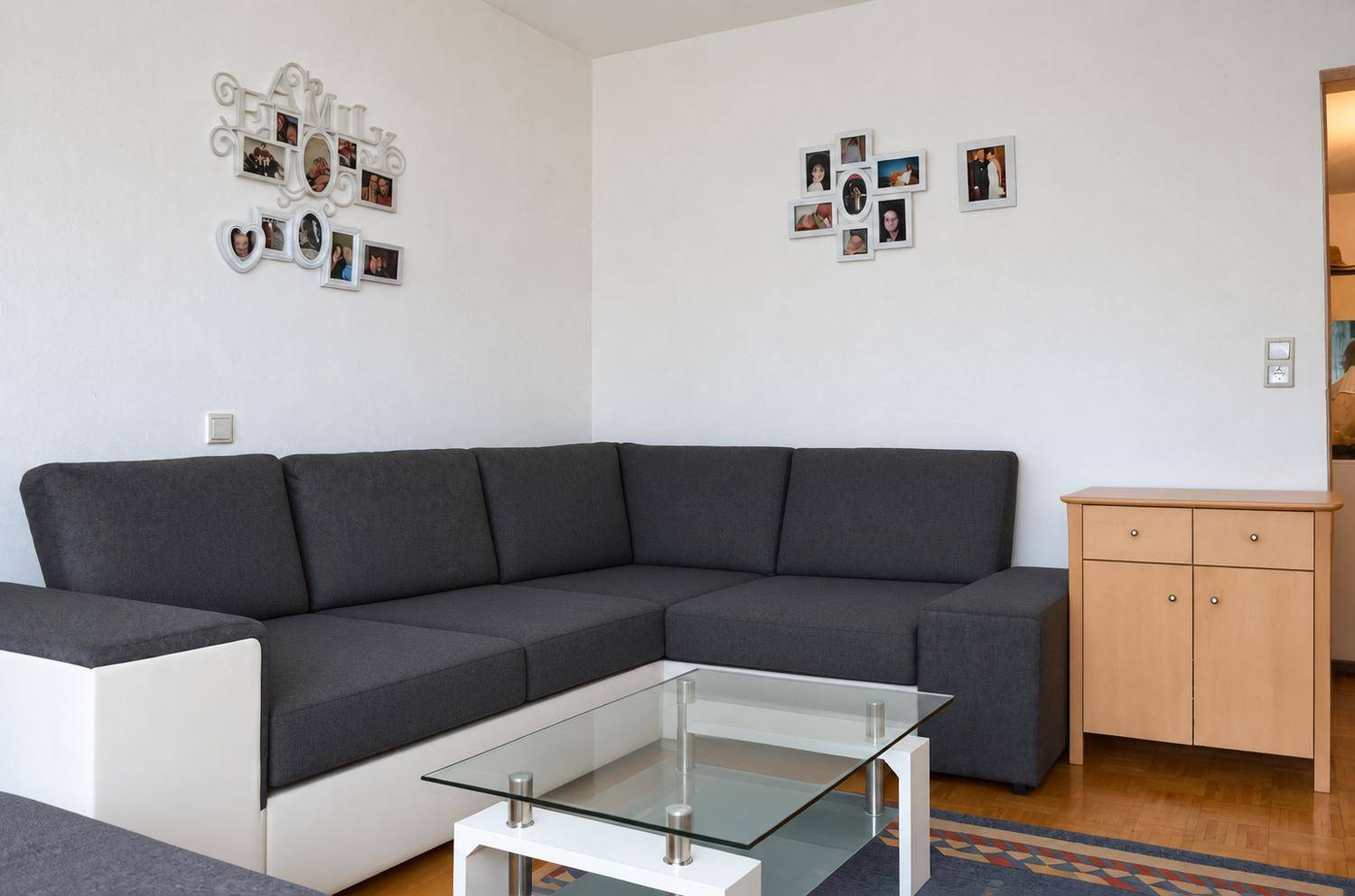 Wohnzimmer mit modernem TV-Möbel, Regalen und Zugang zu einem hellen Flur.