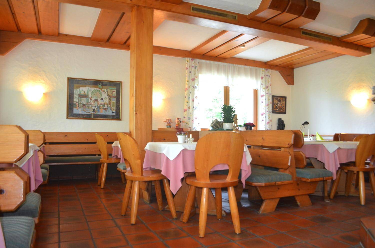 Heller Speisesaal mit traditionellen Holzmöbeln und sichtbaren Deckenbalken.