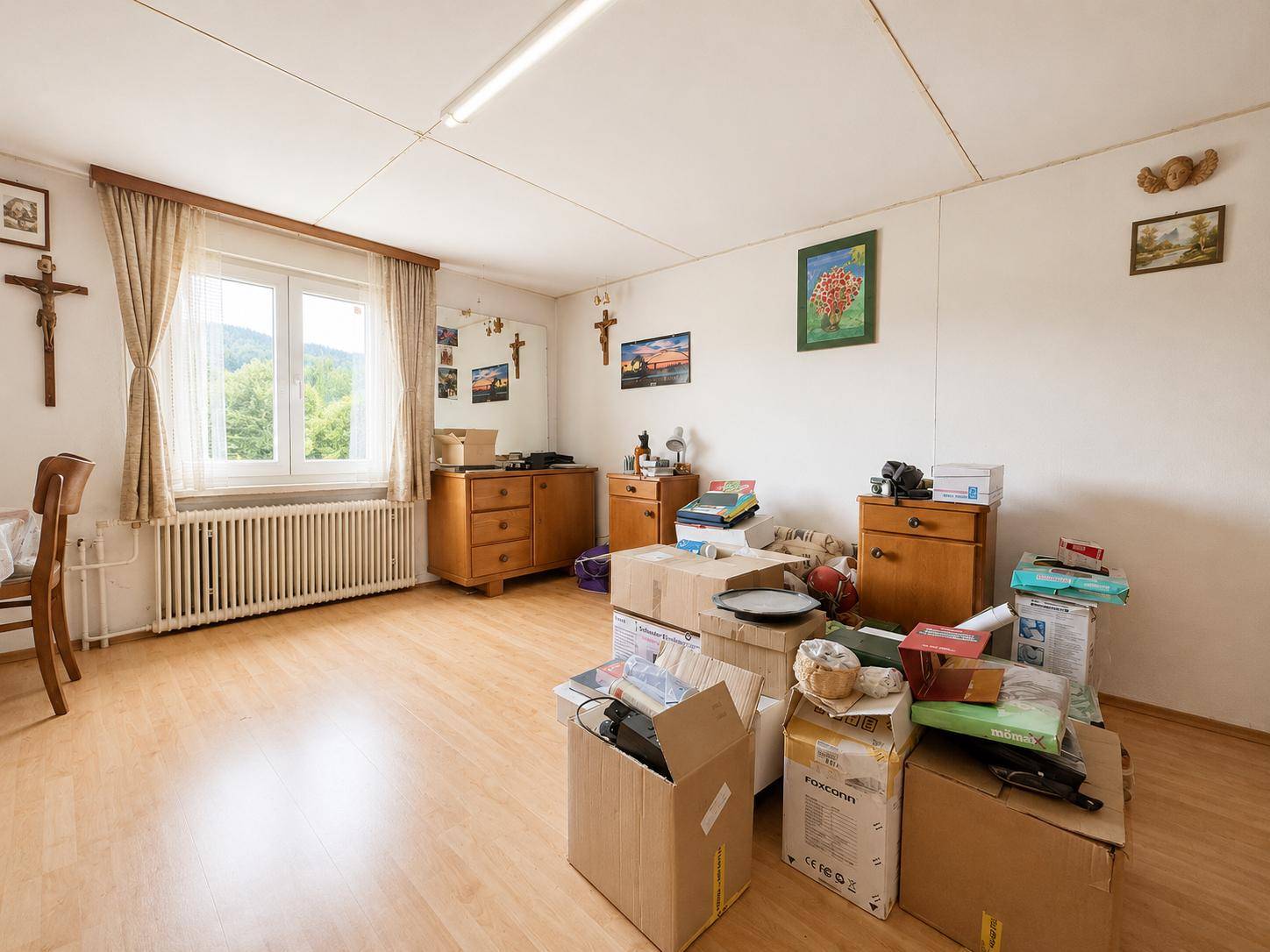 Geräumiges Zimmer mit Laminatboden, Fenster und gestapelten Umzugskartons.
