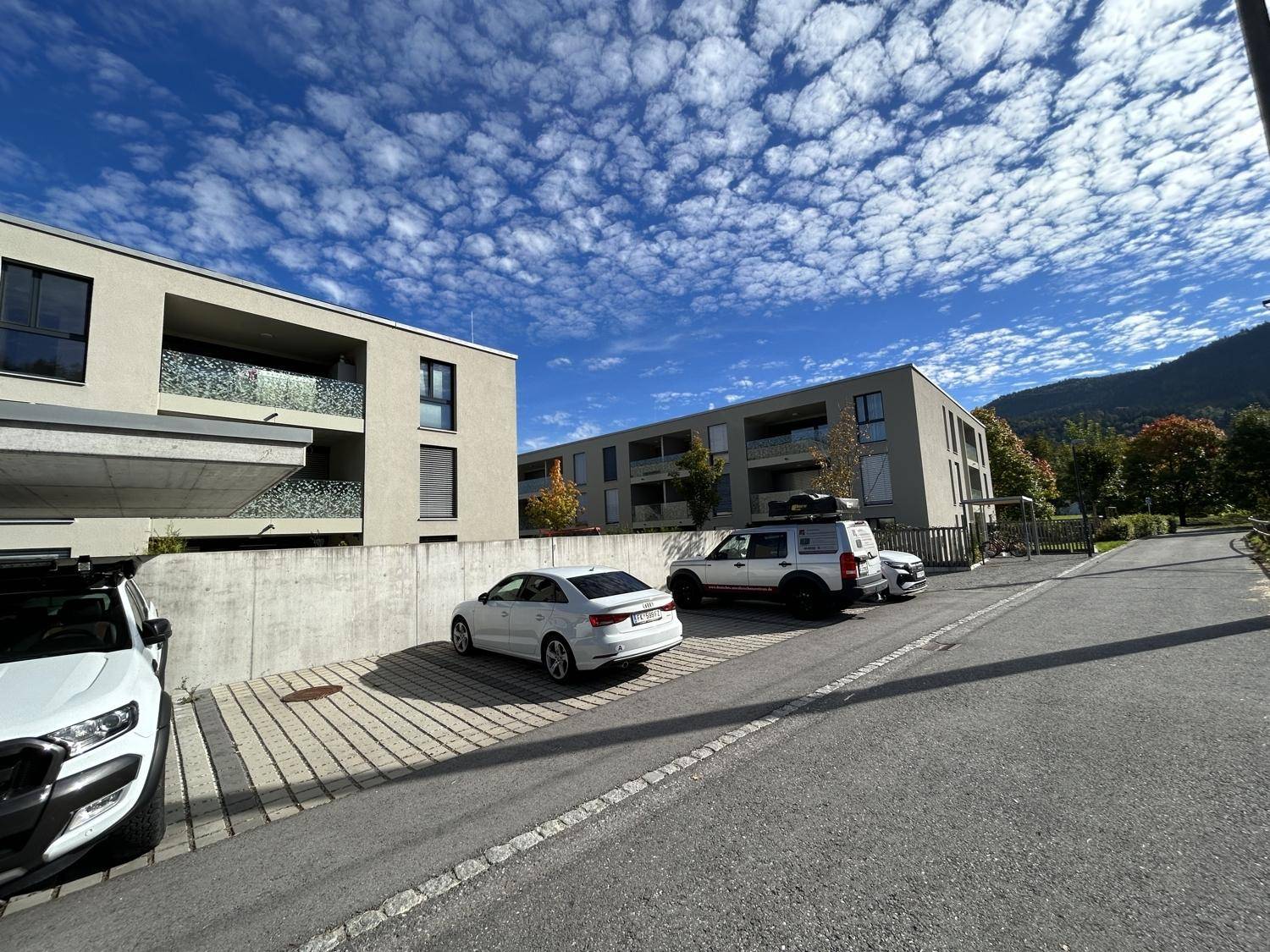 Mehrere moderne Wohngebäude mit Balkonen und Außenparkplätzen unter einem weiten blauen Himmel.