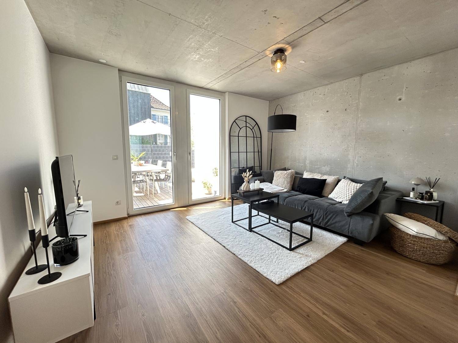 Gemütliches Wohnzimmer mit großem Sofa, Holzboden und Zugang zur sonnigen Terrasse.
