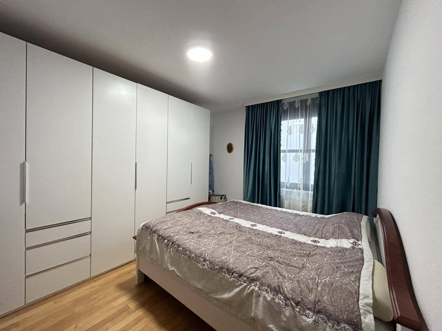 Geräumiges Schlafzimmer mit Doppelbett, großen Kleiderschränken und Parkettboden.