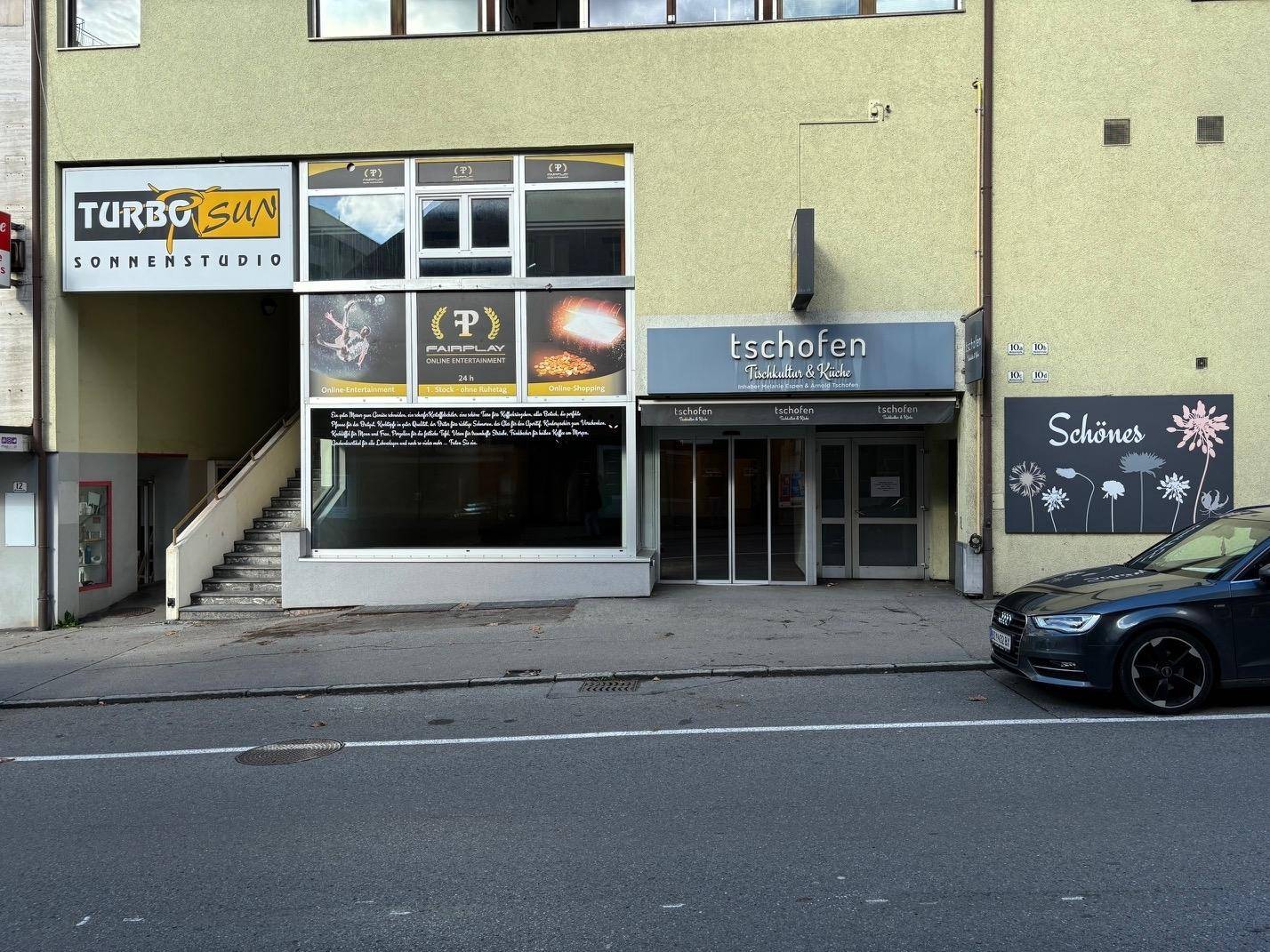 Nahaufnahme der Geschäftsfassade im Erdgeschoss mit Schaufenstern und Eingängen.