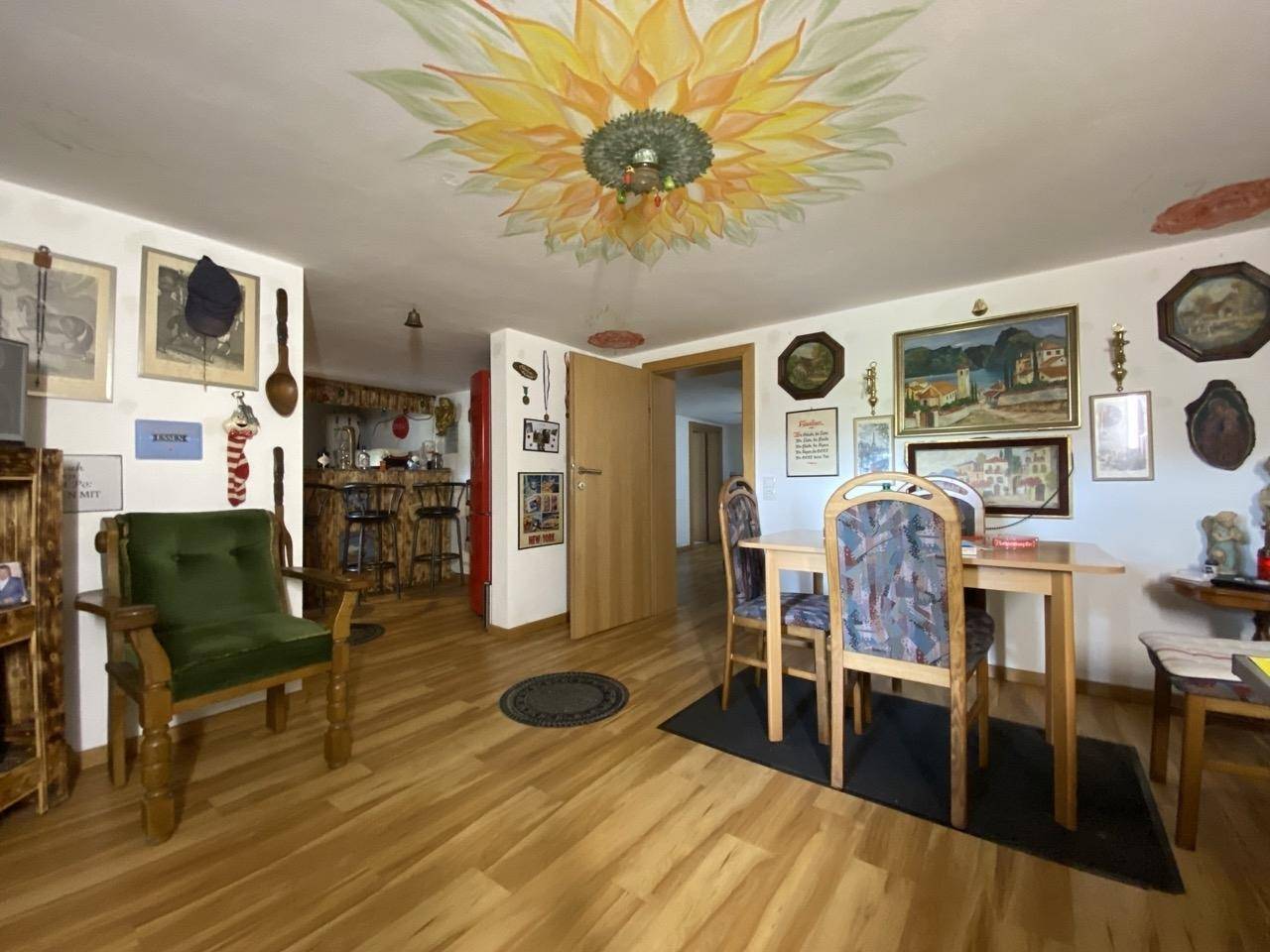 Wohn- und Essbereich mit Holzboden, traditioneller Dekoration und bemalter Decke.