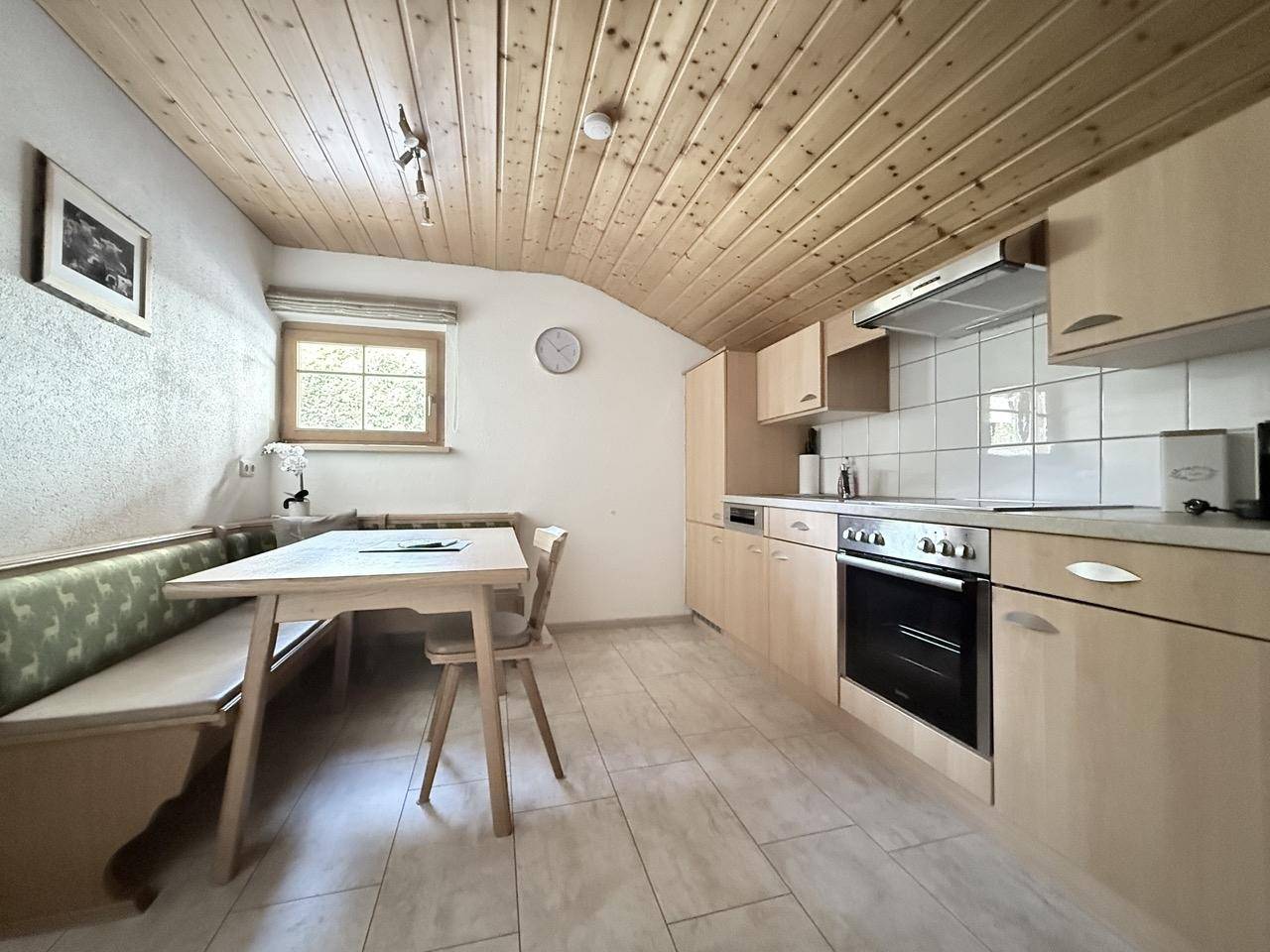 Traditionelle Küche mit Essecke, Holzdecke und Einbaugeräten in hellem Holzdesign.