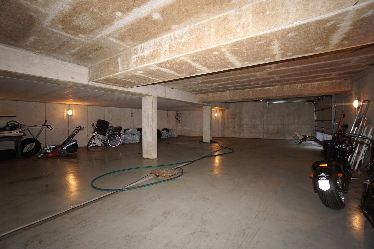 Geräumige Tiefgarage oder Kellerraum mit Betonwänden, Boden und Abstellmöglichkeiten für Fahrzeuge.