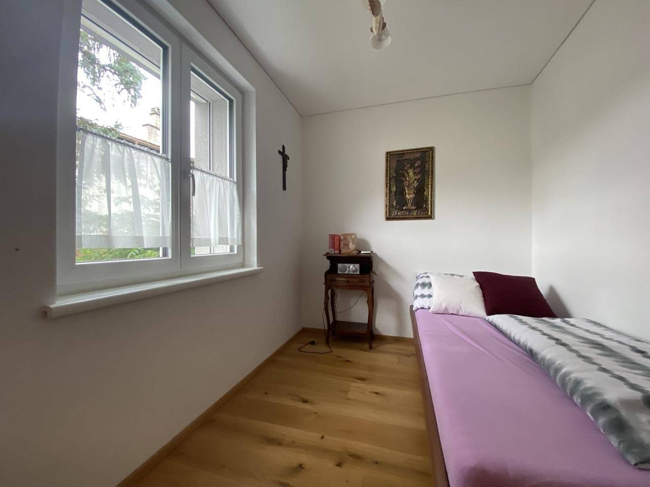 Kleines Schlafzimmer mit Einzelbett, Holzboden und Fenster.