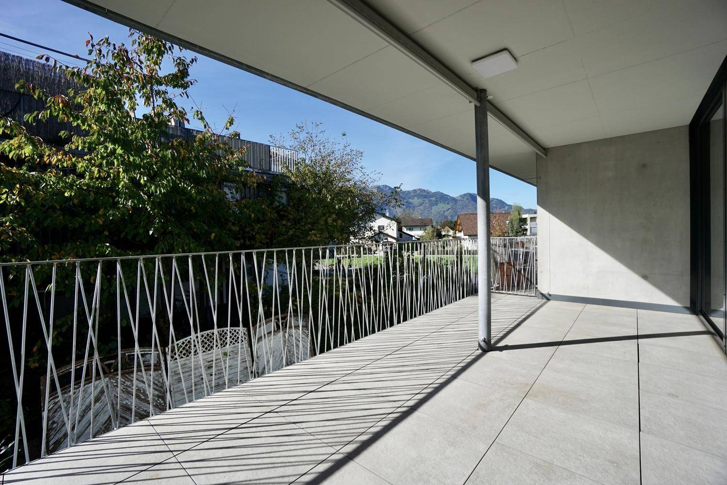 Geräumiger Balkon mit Fliesenboden, modernem Geländer und Bergblick.