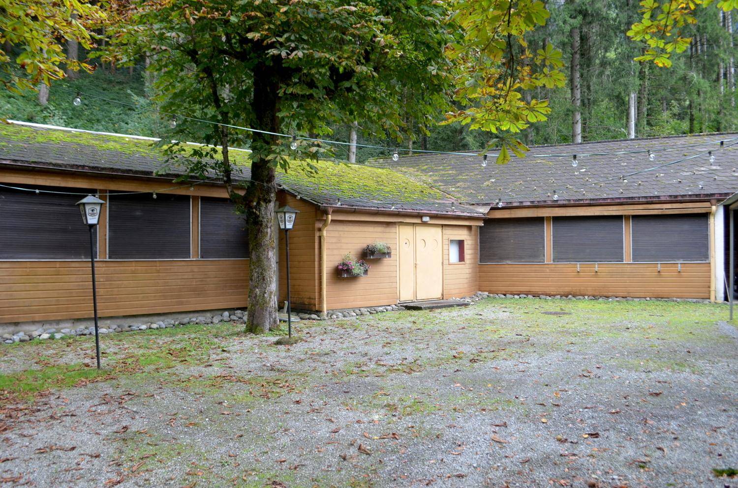 Nebengebäude mit Holzfassade, begrüntem Dach und Kiesfläche davor.