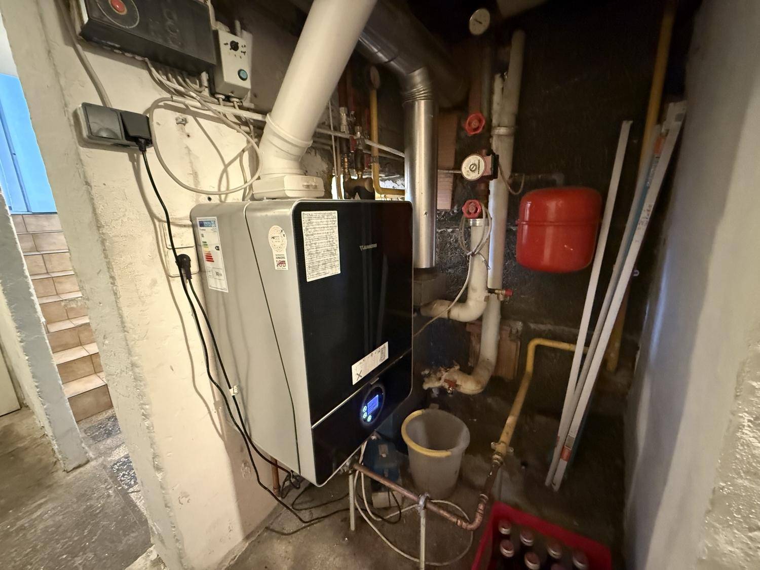 Heizungsraum im Keller mit moderner Heizungsanlage und sichtbaren Rohren.