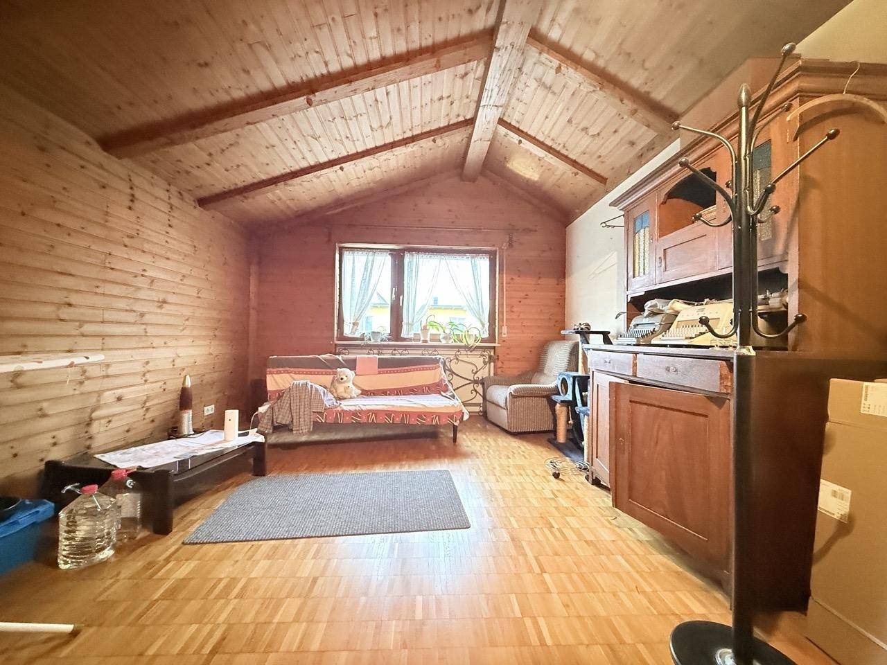 Dachzimmer mit sichtbaren Holzbalken, Holzvertäfelung und Dachschräge, die Gemütlichkeit schafft.