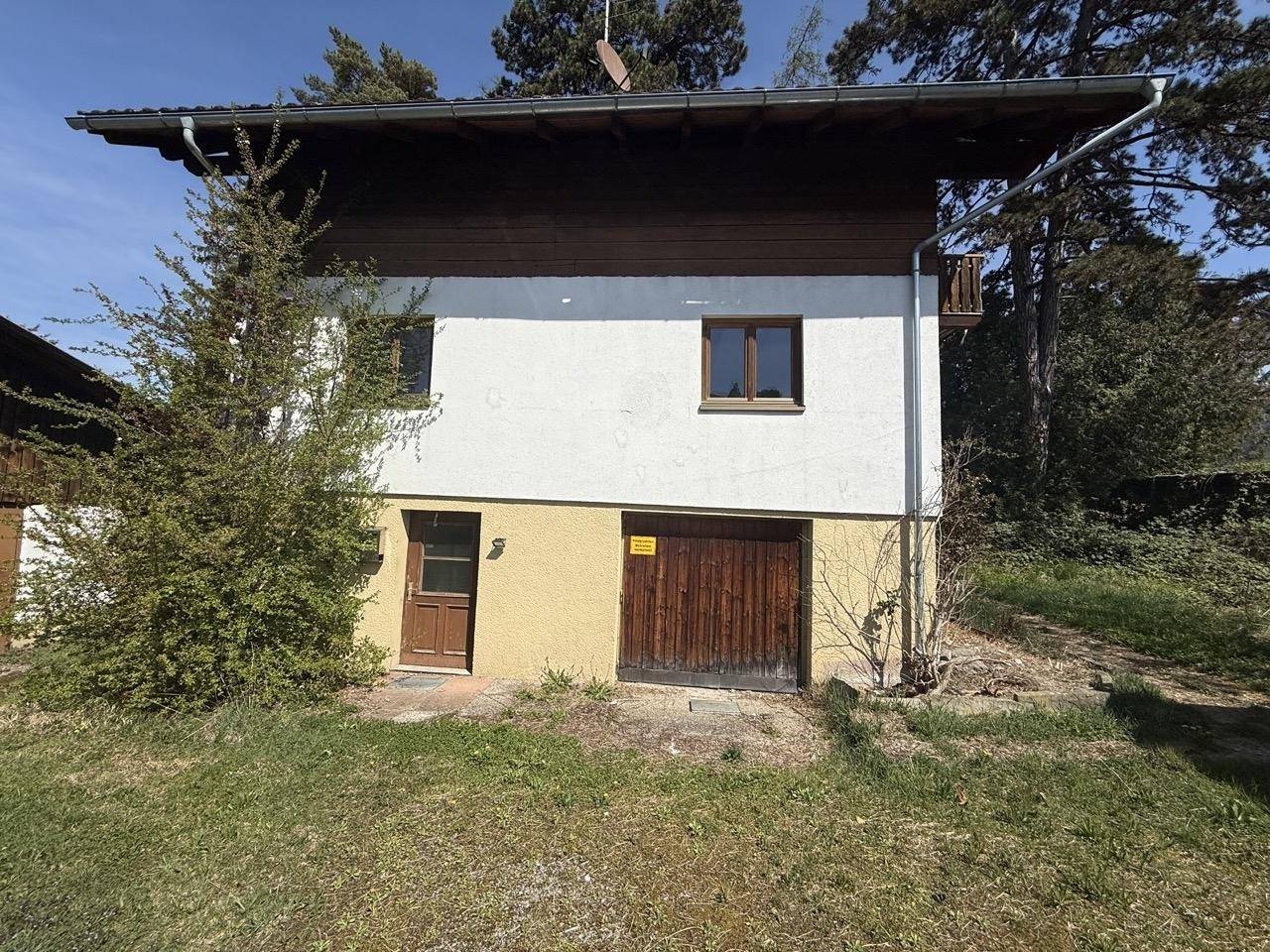 Nahaufnahme der Hausfassade mit Holzelementen und Zugang zum Kellerbereich.