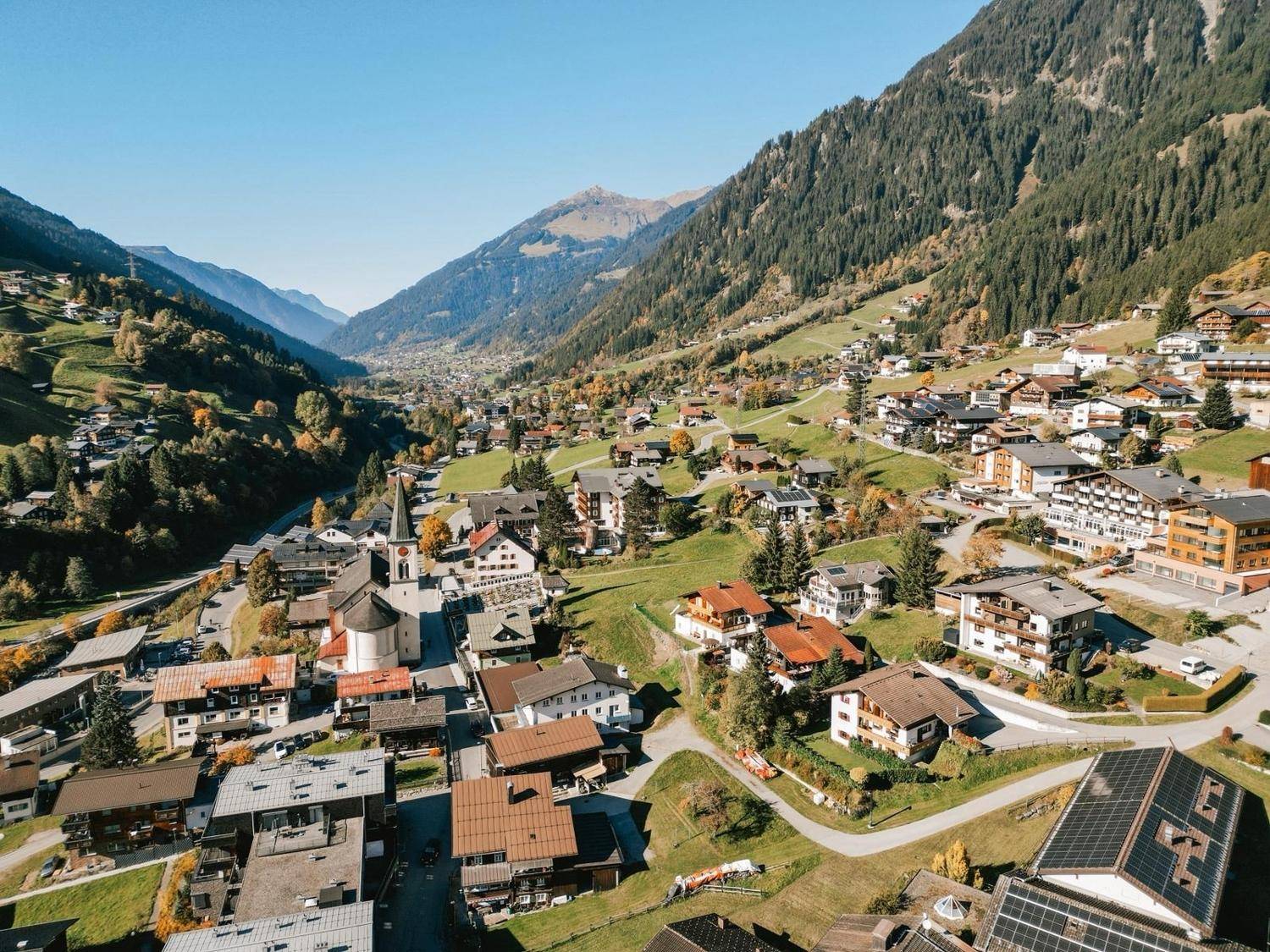 Spektakulärer Panoramablick über ein weites Tal mit einem Dorf und majestätischen Bergen.