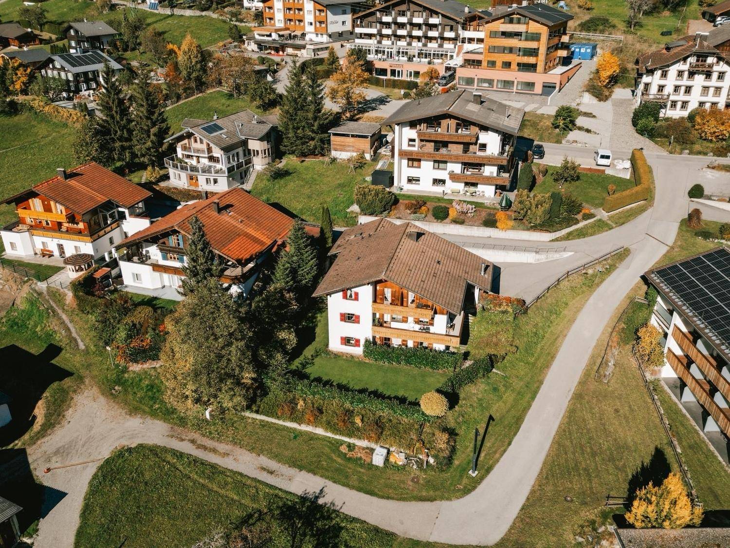 Panoramablick aus der Vogelperspektive auf ein charmantes Bergdorf mit traditionellen Häusern und üppiger Natur.