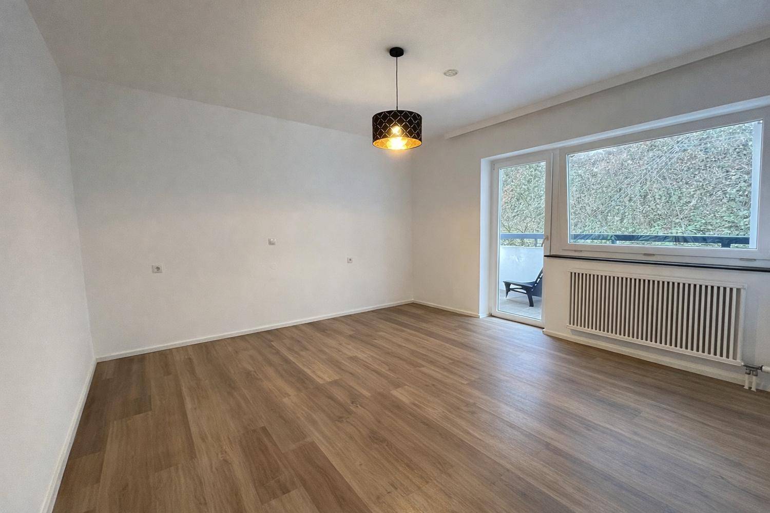 Geräumiges, helles Zimmer mit Laminatboden und direktem Zugang zum Außenbereich.