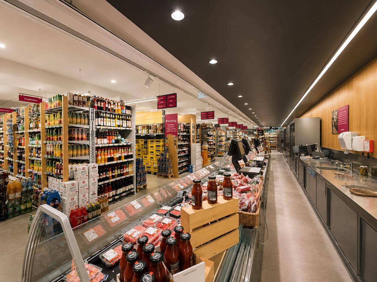 Innenansicht eines modernen Supermarktes mit gut gefüllten Regalen, Kühltheken und einer Servicetheke.