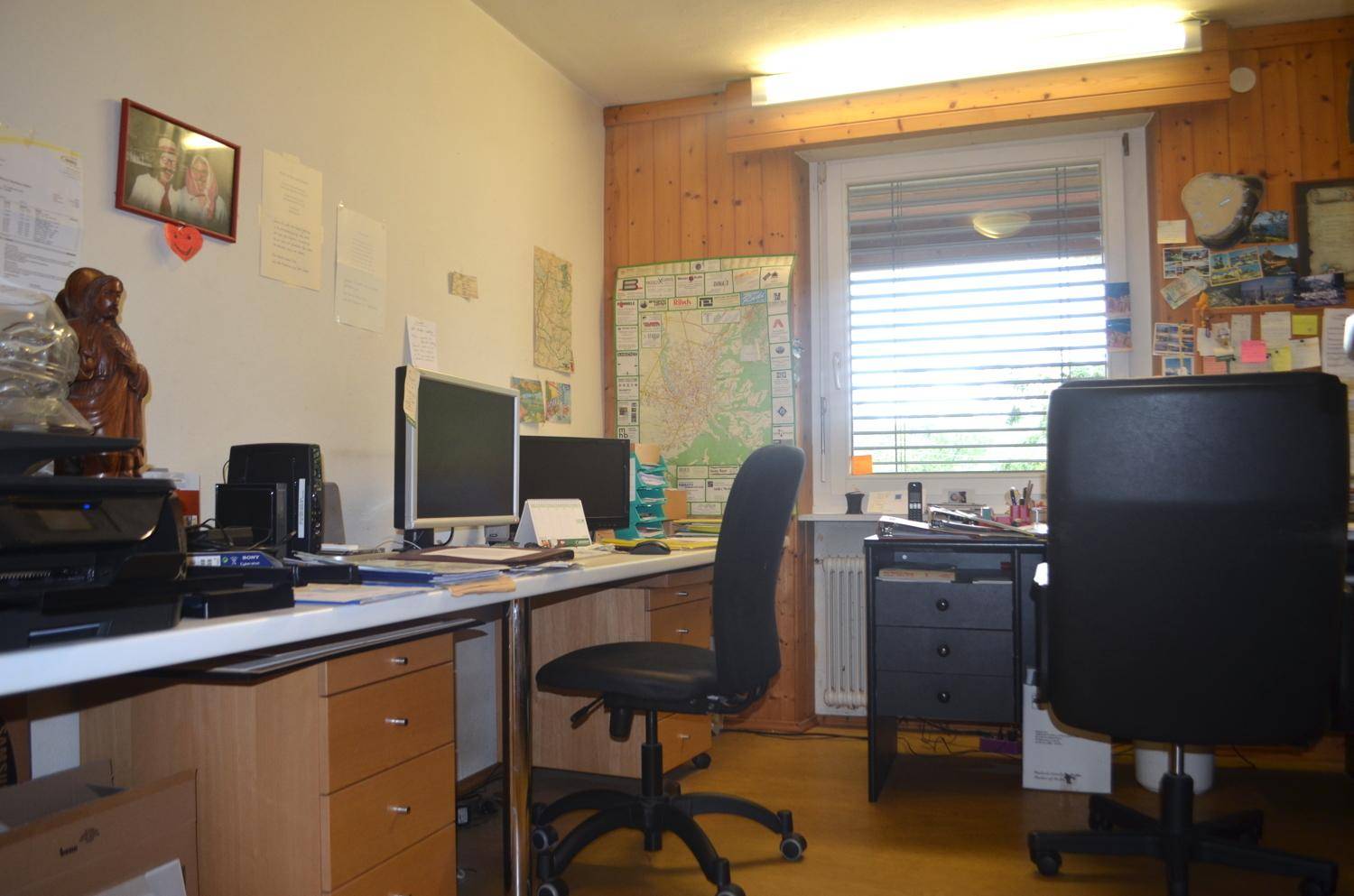 Funktionales Büro mit zwei Arbeitsplätzen, Holzvertäfelung und Fenster.