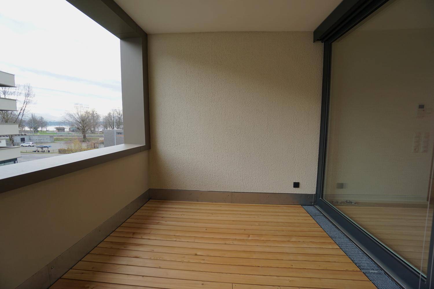 Geräumiger Balkon mit Holzboden und weitem Blick auf den See und die Umgebung.