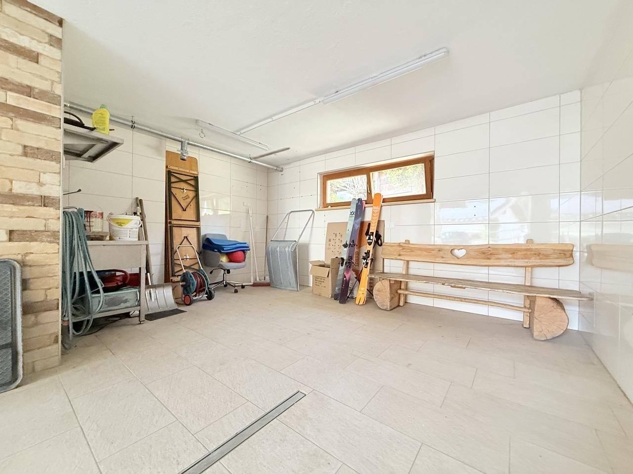 Geräumige Garage oder Abstellraum mit Fliesenboden, Fenster und Stauraum.