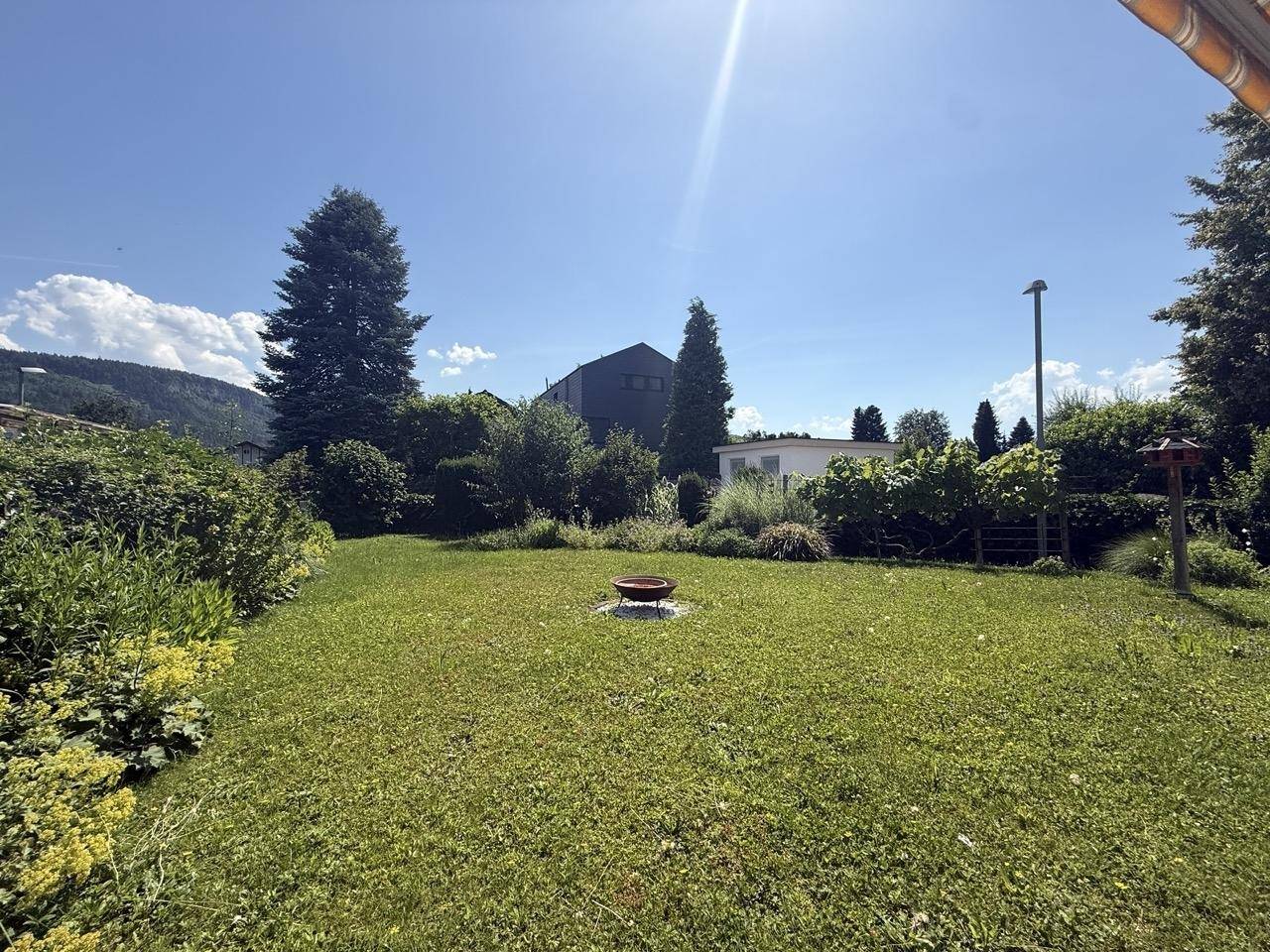 Der weitläufige Garten mit Rasenfläche und einer Feuerstelle lädt zu gemütlichen Abenden ein.
