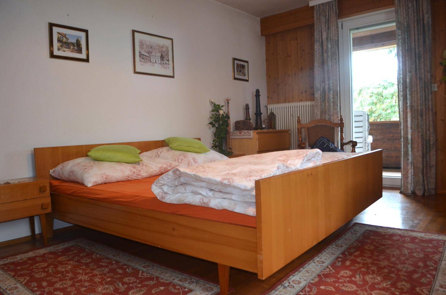 Schlafzimmer mit Doppelbett, Holzmöbeln und direktem Zugang zu einem Balkon.