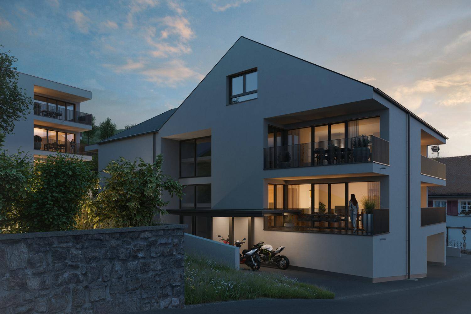 Moderne Architektur eines neuen Mehrfamilienhauses mit großen Fenstern und Balkonen bei Sonnenuntergang.