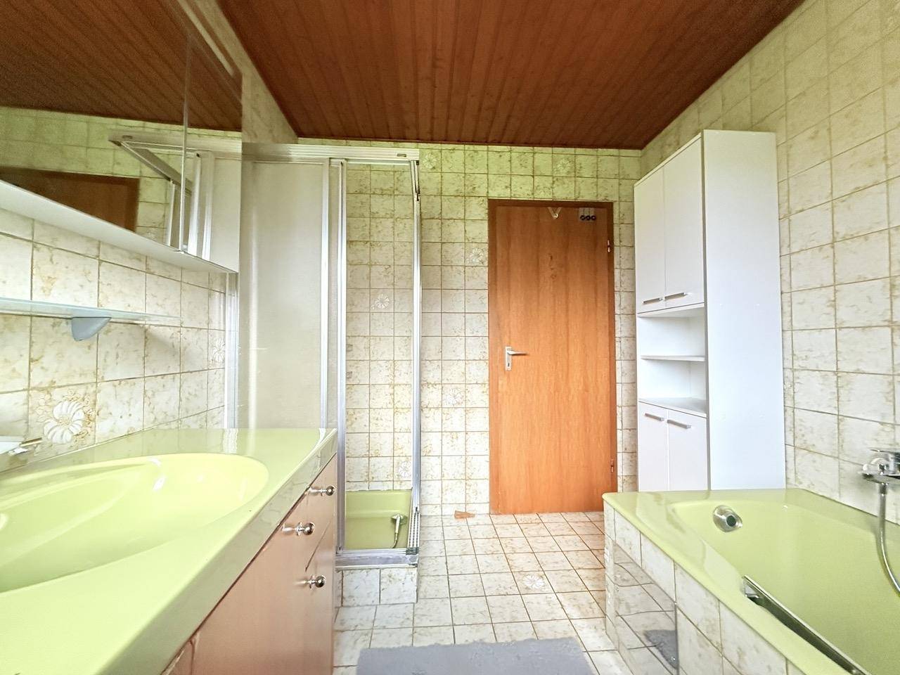 Badezimmer mit grüner Badewanne, Dusche und Einzelwaschbecken, typisch für die 80er Jahre.