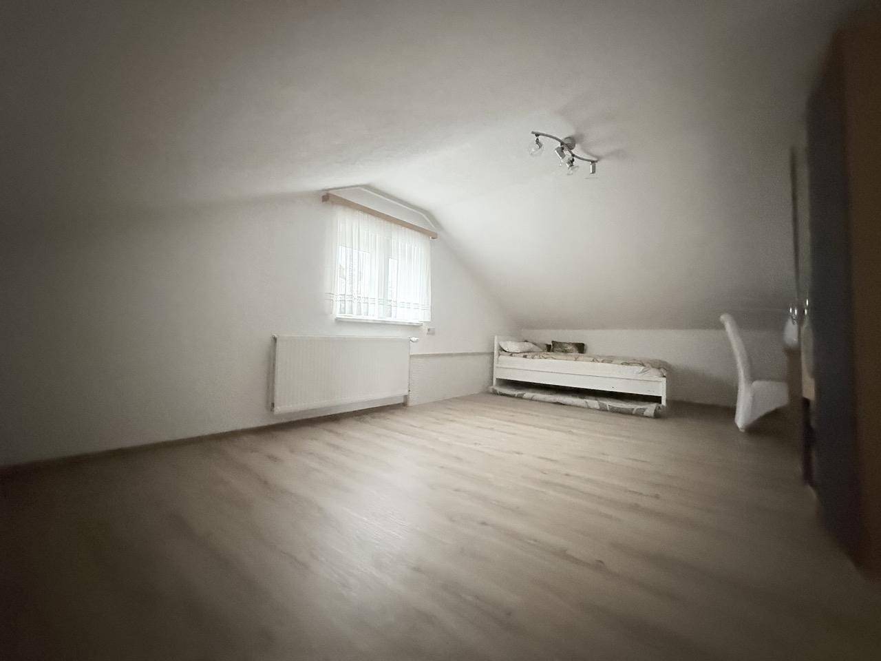 Schlafzimmer im Dachgeschoss mit schräger Decke und Laminatboden.