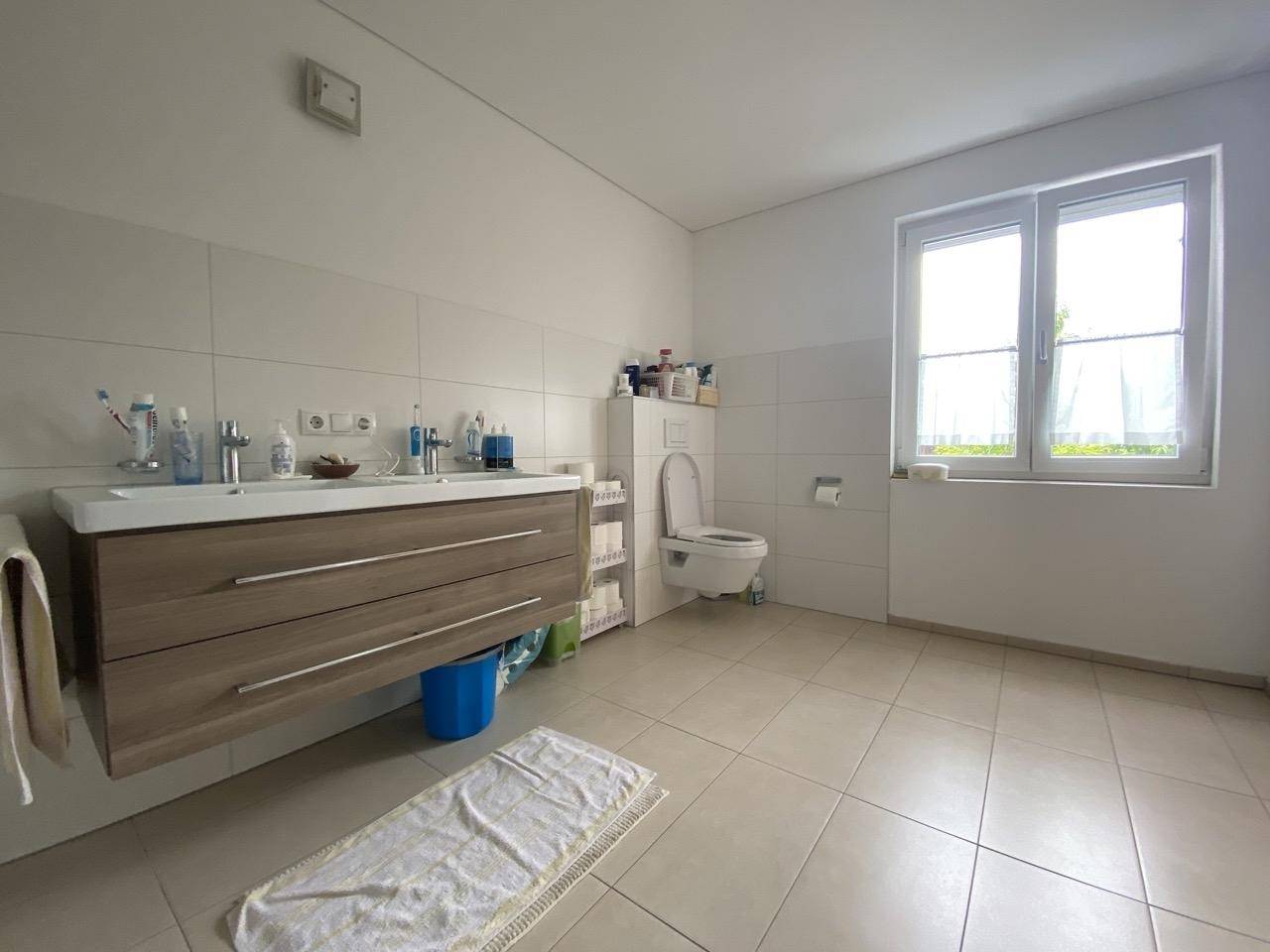 Helles Badezimmer mit Fenster, wandhängendem WC und modernem Waschtisch.