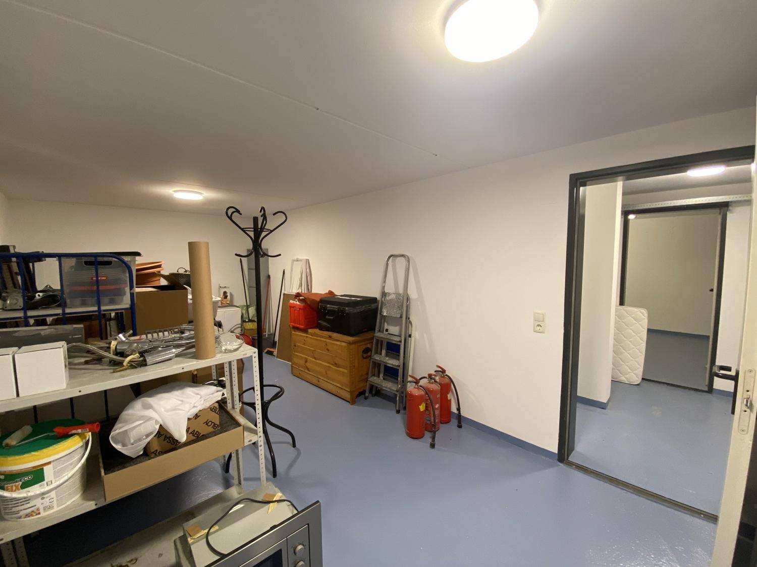 Praktischer Lagerraum mit blauem Vinylboden und weißen Wänden, bietet viel Stauraum.