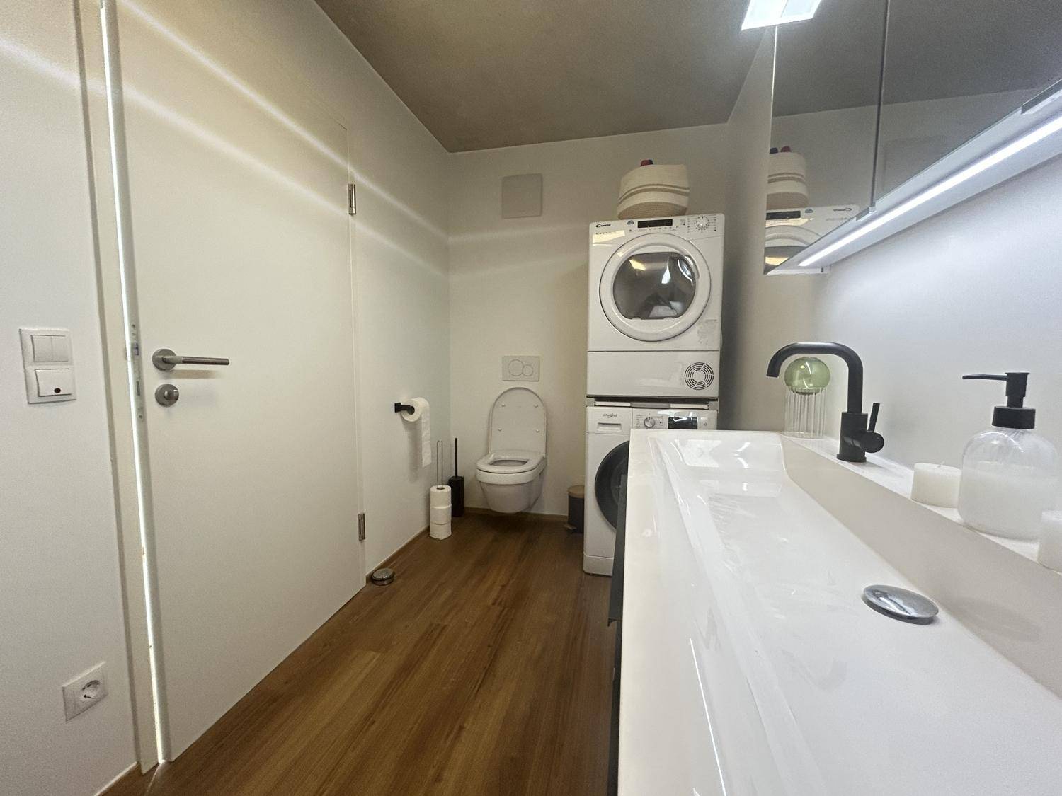 Praktischer Waschraum mit Waschmaschine, Trockner und Toilette, ideal für den Alltag.