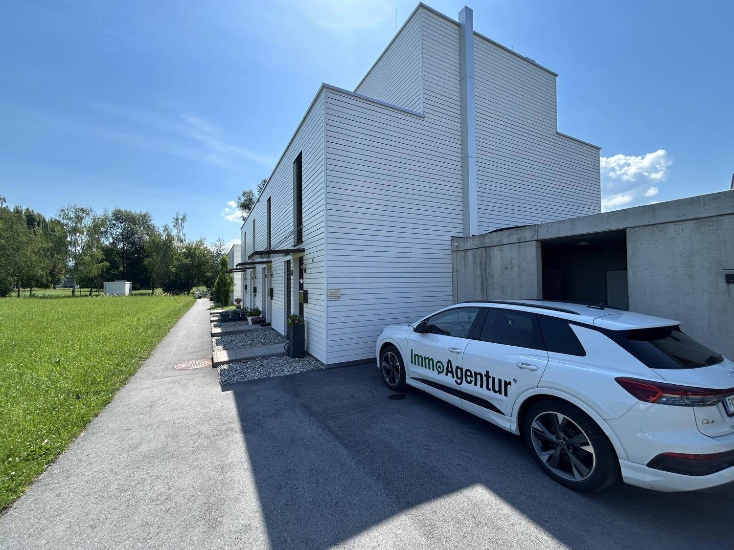 Moderne Reihenhäuser mit weißer Holzfassade und gepflegter Außenanlage.