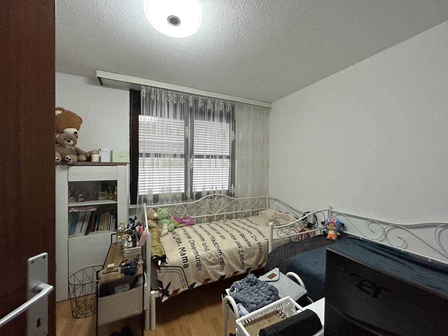 Helles Kinderzimmer mit Einzelbett, weißen Möbeln und Parkettboden.
