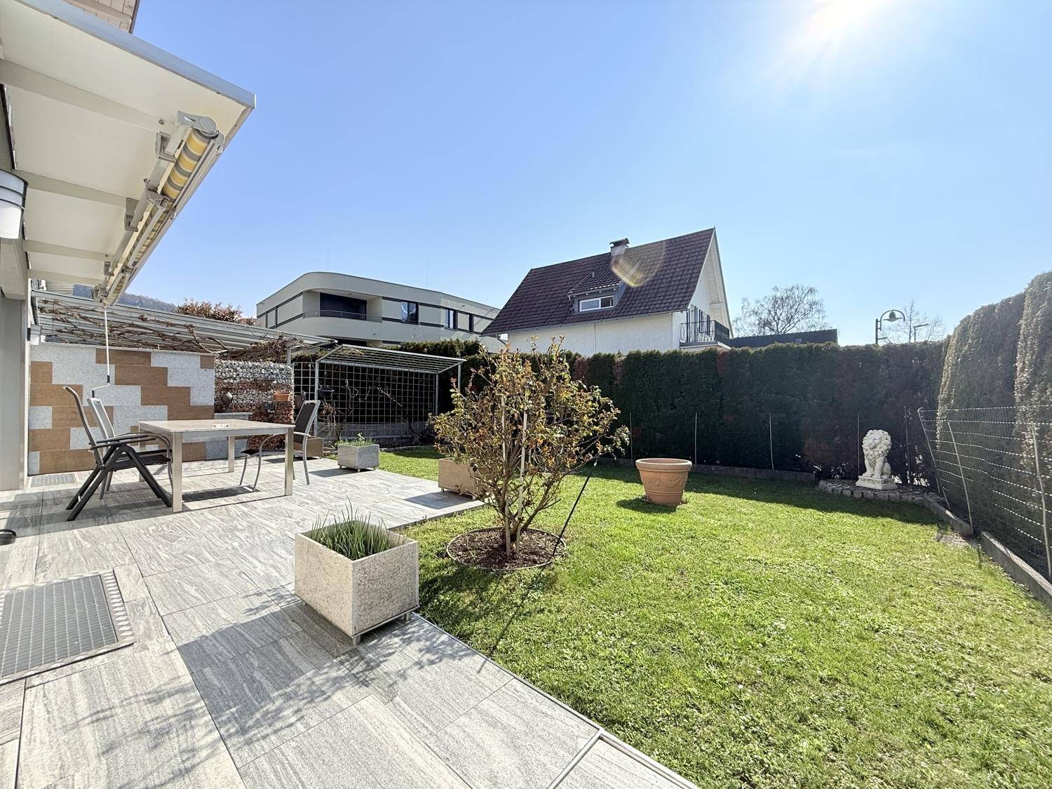 Gepflegter Gartenbereich mit Terrasse, Sitzgelegenheiten und Blick auf die umliegende Bebauung.