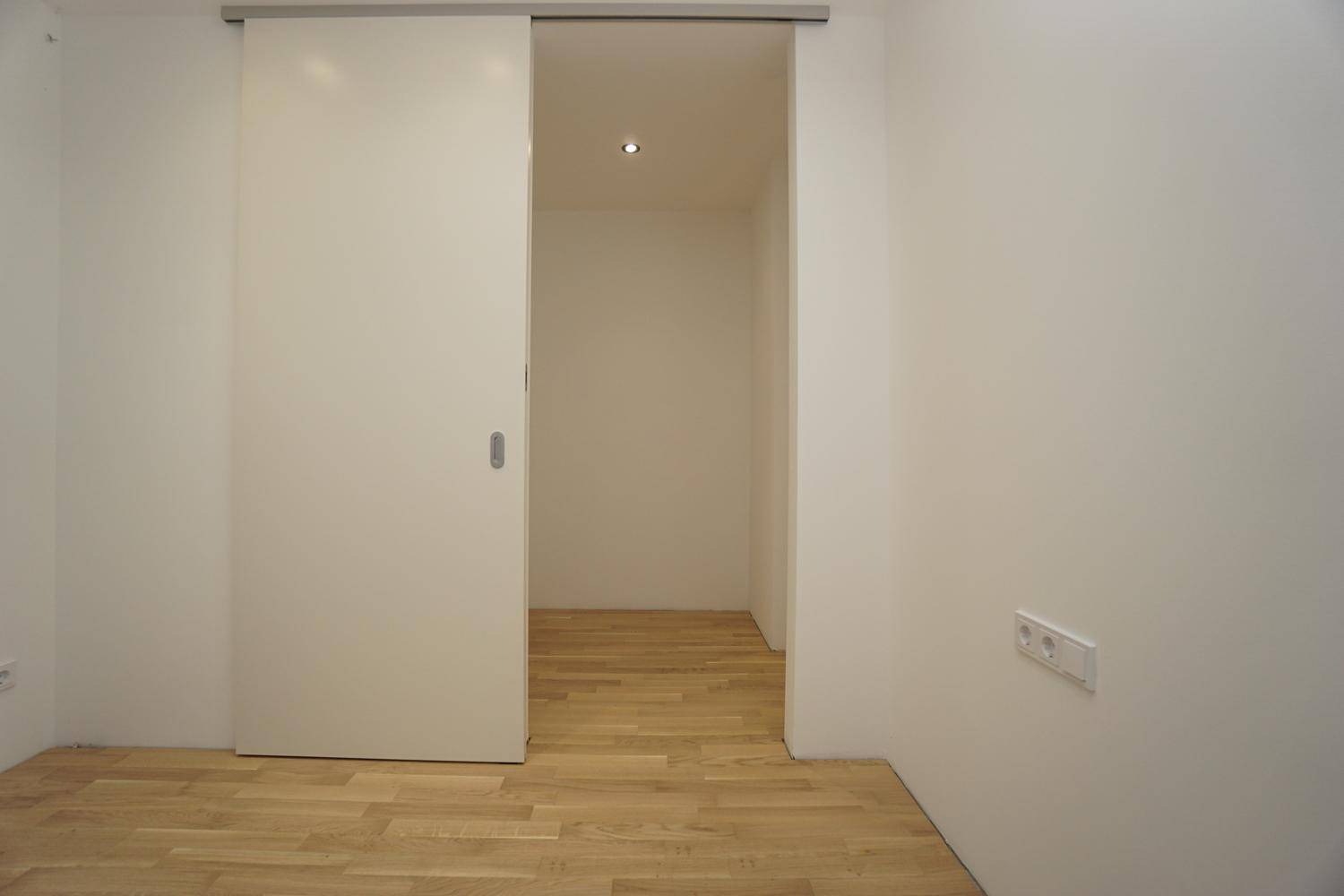 Detailansicht einer modernen Schiebetür in einem hellen Raum mit Holzparkett.