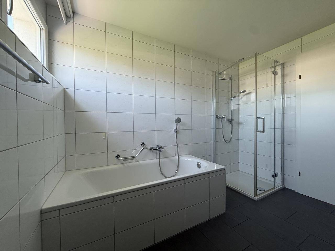 Geräumiges Badezimmer mit eingebauter Badewanne und separater Glasdusche.