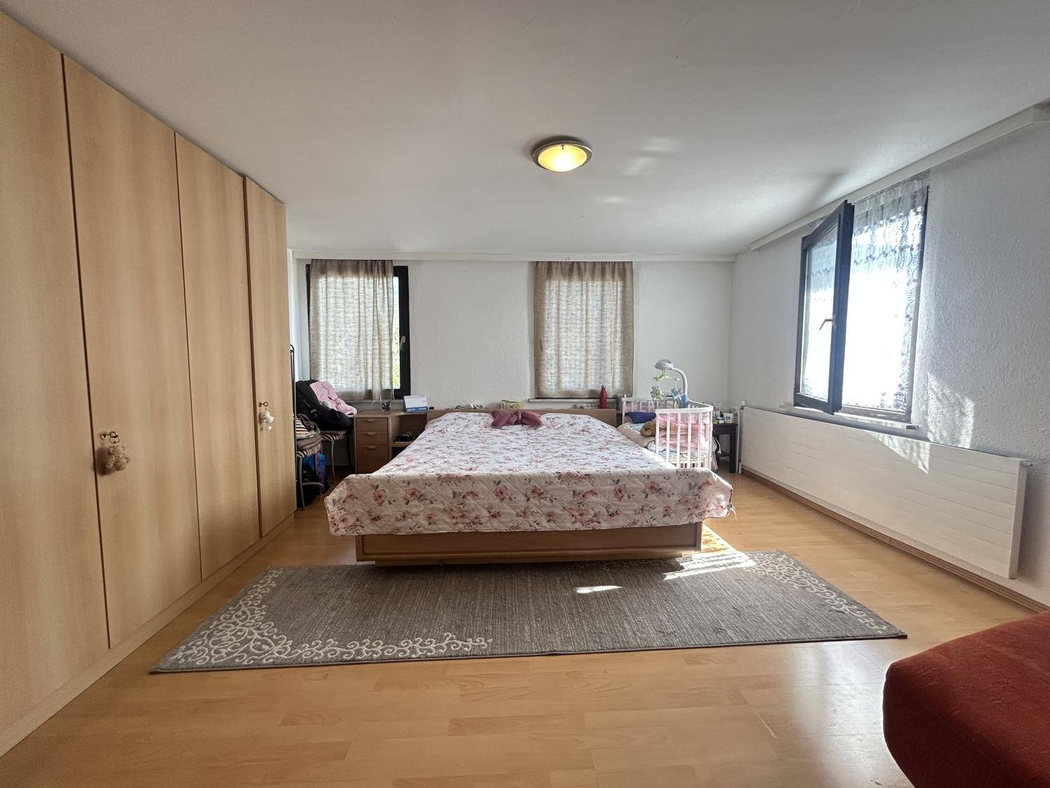 Großes Schlafzimmer mit Doppelbett, Einbauschränken und Fenstern, die viel Tageslicht hereinlassen.