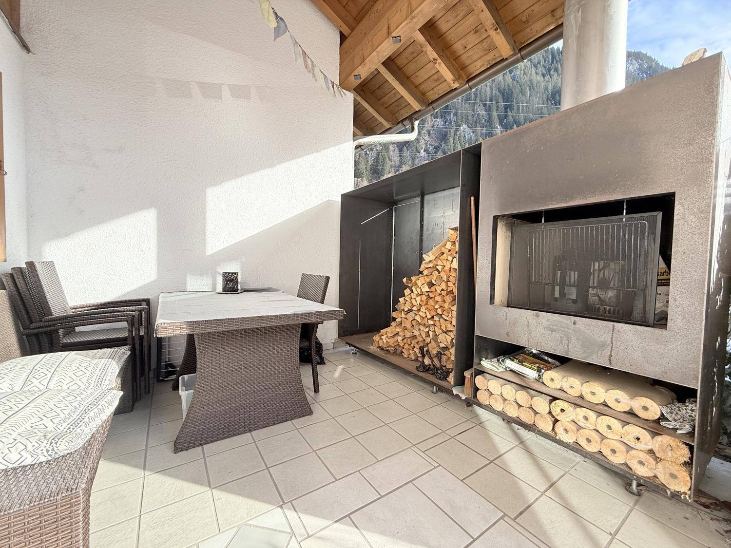 Gemütliche Terrasse mit Outdoor-Möbeln, Grillbereich und Blick auf die umliegende Berglandschaft.