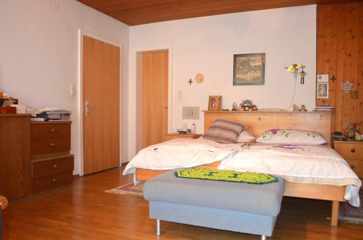 Schlafzimmer mit zwei Einzelbetten, Holzmöbeln und Holzvertäfelung an einer Wand.