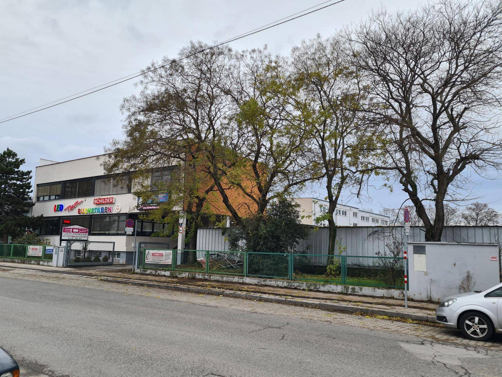Weitwinkelansicht des Gewerbegebäudes von der Straße aus, umgeben von Bäumen und der Nachbarschaft.