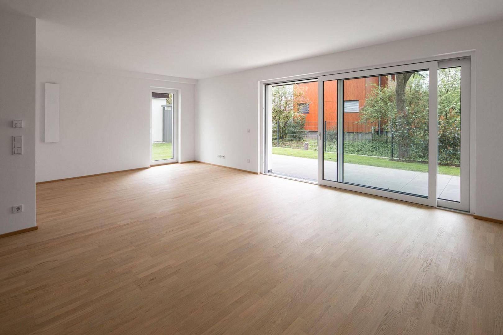 Lichtdurchflutetes Wohnzimmer mit Schiebetüren zum Garten und Blick auf die Nachbarschaft.