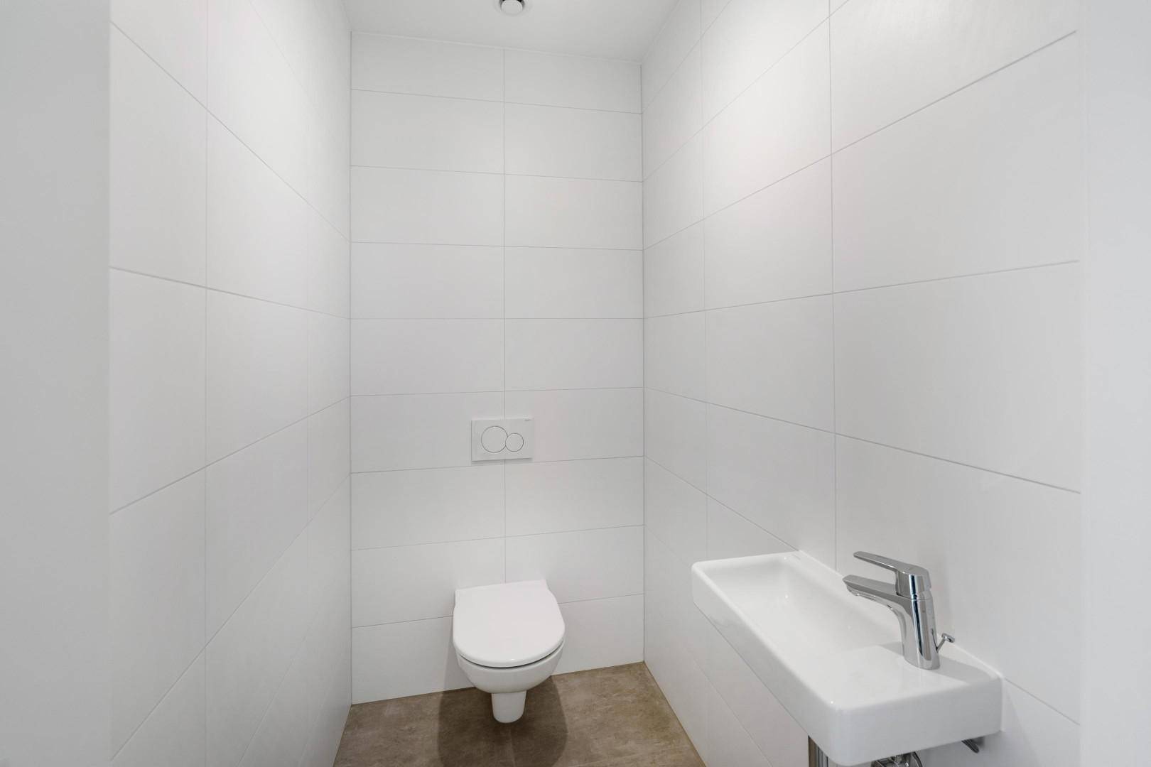 Separates Gäste-WC mit wandhängender Toilette und kleinem Waschbecken.