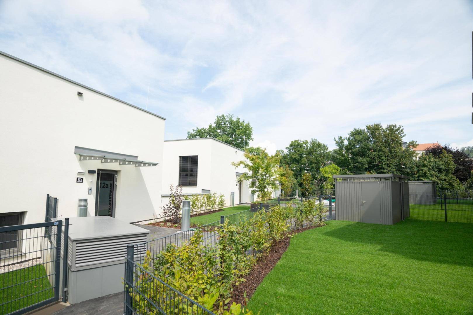 Mehrere moderne Gebäude mit gepflegten Grünflächen und Gemeinschaftsbereichen.