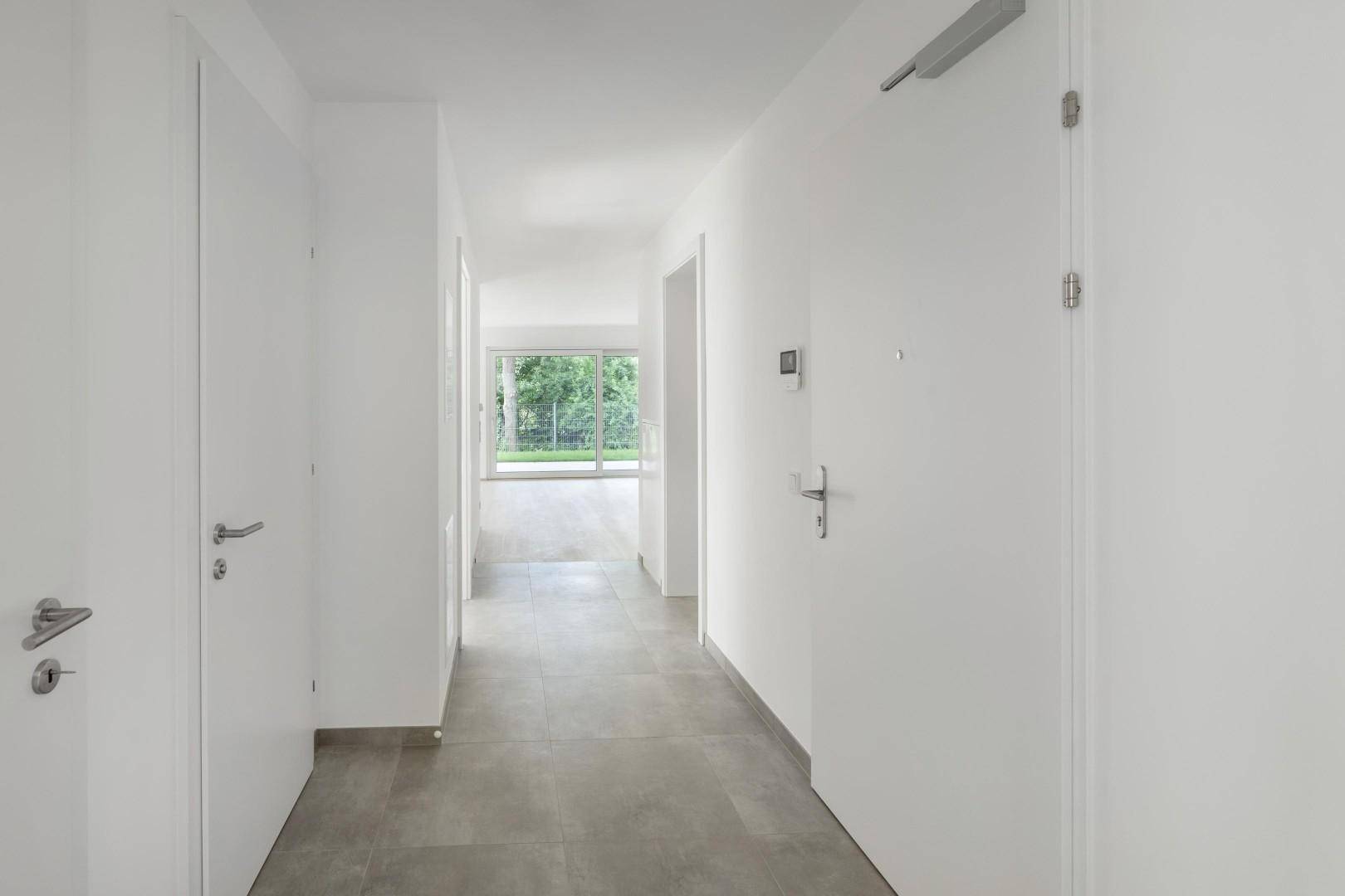 Heller Flur mit modernen Fliesen und Blick in den Wohnbereich mit Garten.